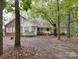 Quaint house featuring a brick facade, white siding, and a charming covered porch with lush, mature trees at 2721 Tara Dr, Monroe, NC 28112