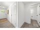 Hallway with plank flooring and white walls leads to a bright window and rooms at 3205 Morning Dr, Charlotte, NC 28208
