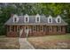 Inviting brick home with dormer windows, a well-manicured lawn, and a charming walkway leading to the front door at 328 Earl Griffin Rd, Monroe, NC 28112