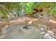 Cozy stone fire pit with retaining wall, offering a relaxing outdoor space surrounded by trees at 3329 Winnipeg Cir, Charlotte, NC 28210