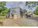 View of blue home exterior with covered porch, shed, mature trees, and gravel driveway at 405 Belva St, Kannapolis, NC 28081