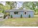Quaint blue home features wooden shutters, a covered porch, and verdant lawn at 405 Belva St, Kannapolis, NC 28081