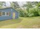Side exterior of charming blue home boasts a yellow door and lush, green lawn at 405 Belva St, Kannapolis, NC 28081