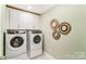 Well-lit laundry room featuring a washer and dryer, white cabinets, and decorative wall art at 4248 Black Ct # 232, Harrisburg, NC 28075
