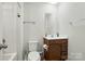 This bathroom has a wood vanity, white sink, toilet, mirror, and shower with white walls at 4439 Wild Ridge Dr, Charlotte, NC 28215