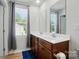 Bathroom featuring a double vanity with wood cabinets, a large mirror, and a window at 4439 Wild Ridge Dr, Charlotte, NC 28215
