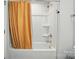 Bathroom includes a bathtub with shower, orange decorative curtain, and white walls at 4439 Wild Ridge Dr, Charlotte, NC 28215