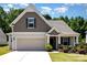 Charming home featuring a two-car garage, manicured lawn, and inviting front porch at 5053 Arbordale Way, Mount Holly, NC 28120
