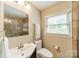 Bright bathroom featuring a tiled shower, vanity with sink, toilet, and window with natural light at 5522 Sharon Rd, Charlotte, NC 28210