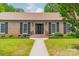 Close up on the front of a brick home with black shutters and a well-maintained front lawn at 5522 Sharon Rd, Charlotte, NC 28210