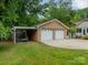 Brick detached garage with white doors, a covered outdoor seating area, and green lawn in the backyard at 5522 Sharon Rd, Charlotte, NC 28210