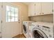 Functional laundry room with modern washer and dryer, overhead storage cabinets, and access to the outside at 5522 Sharon Rd, Charlotte, NC 28210
