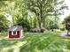 View of backyard shed, landscaped yard, and mature trees, offering privacy and tranquility at 6007 Patrick Pl, Charlotte, NC 28210