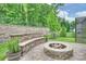 Cozy outdoor fire pit area with a stone bench, lush greenery, and a serene backyard setting at 7209 Brookline Pl, Huntersville, NC 28078
