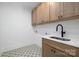 Well-lit laundry room with patterned tile floor, built-in sink and storage cabinets at 816 Tennyson Dr, Charlotte, NC 28208