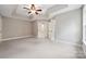 Open bedroom with tray ceilings, a ceiling fan, soft carpeting, and door to the en-suite bathroom at 817 Quince Ct, Indian Trail, NC 28079