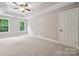 Light-filled bedroom with tray ceilings, a ceiling fan, plush carpeting, and ample windows at 817 Quince Ct, Indian Trail, NC 28079