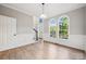 Open-concept living room with hardwood floors, wainscoting, and a large window overlooking the front yard at 817 Quince Ct, Indian Trail, NC 28079