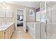 Bright bathroom featuring double vanity, bathtub, and shower, with a door leading to the main bedroom at 9101 Strattonville Ct, Huntersville, NC 28078
