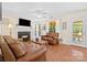 Cozy living room with brick fireplace, hardwood floors, ceiling fan, and tons of natural light at 9101 Strattonville Ct, Huntersville, NC 28078