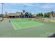 An outdoor tennis court with net overlooks the clubhouse in a serene setting with lush trees and plants at 10201 Daufuskie Dr, Charlotte, NC 28278