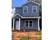 Two-story home features gray siding, white trim, covered porch and a well-lit, eye-catching, exterior elevation at 115 Allen St, Rock Hill, SC 29730