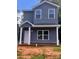 Two-story home features gray siding, white trim, covered porch and a well-lit, eye-catching, exterior elevation at 115 Allen St, Rock Hill, SC 29730