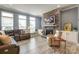 Open-concept living room with a stone fireplace, hardwood floors, large windows, and comfortable seating at 13624 Jacks Ln, Pineville, NC 28134