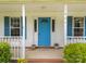 A close-up of the bright blue front door with sidelights and plants in pots on a brick entry way at 1401 Thompson Ave, Charlotte, NC 28216