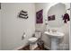 Stylish half bathroom featuring a pedestal sink, decorative mirror, and modern fixtures at 145 Marron Dr, Indian Trail, NC 28079