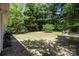 View of a grassy backyard with mature trees, featuring a small playset and a fire pit at 16117 Wrights Ferry Rd, Charlotte, NC 28278