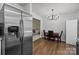 View of the dining room adjacent to the kitchen, featuring stainless steel refrigerator and a modern chandelier at 16117 Wrights Ferry Rd, Charlotte, NC 28278