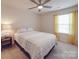A neutral bedroom is decorated with a ceiling fan, a bedside table, and a window with yellow curtains at 2037 Christopher Wood Ct, Indian Land, SC 29707