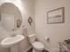 Compact powder room with pedestal sink, round mirror, and neutral decor at 2037 Christopher Wood Ct, Indian Land, SC 29707
