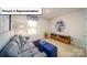 Comfortable bonus room with gray sofa, blue ottoman, and stylish decor at 3018 Sassafras Trl, Gastonia, NC 28056