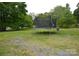 Lush backyard featuring a trampoline, mature trees, and open space perfect for outdoor activities at 303 Nc Hwy 200 N Hwy, Stanfield, NC 28163