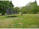 This sprawling backyard has a trampoline, lush trees, and a fire pit, perfect for relaxation at 303 Nc Hwy 200 N Hwy, Stanfield, NC 28163