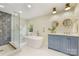 Bright bathroom featuring a modern tub, glass enclosed shower with hexagon tile and blue vanity with dual mirrors at 310 Whitestone Rd, Charlotte, NC 28270