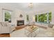 Cozy living room featuring a brick fireplace, hardwood floors, and large windows for ample natural light at 310 Whitestone Rd, Charlotte, NC 28270