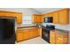 Well-equipped kitchen with wood cabinetry, tiled floors, and black appliances provides efficient functionality at 3327 Flagler Cir, Midland, NC 28107