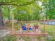 Backyard seating area with a brick-lined fire pit and colorful chairs surrounded by lush greenery and mature trees at 335 Linda St, Salisbury, NC 28146