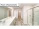 Bathroom with dual sinks, a glass-enclosed shower, and neutral tile, offering modern comfort at 3412 Lacebark Ln, Gastonia, NC 28056