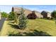 View of a large backyard with mature trees, lawn, and a neighboring brick home at 3424 Windstone Ln, Gastonia, NC 28056