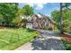 Elegant brick home boasts a manicured lawn, mature trees, and a spacious driveway at 4232 Shannamara Dr, Matthews, NC 28104