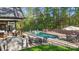 Resort-style backyard featuring a pool, outdoor kitchen, and lounge area surrounded by trees at 425 W North Corner Rd, Lancaster, SC 29720