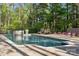Serene backyard pool with a fire pit, stone wall, and black metal fencing offering privacy and tranquility at 425 W North Corner Rd, Lancaster, SC 29720