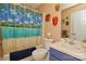 Bathroom with a tropical-themed shower curtain, blue vanity, and decorative wall masks at 4810 Shea Ct, Monroe, NC 28110