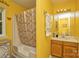 Bright yellow bathroom features a shower-tub combination, a patterned shower curtain, and a wood vanity at 4810 Shea Ct, Monroe, NC 28110
