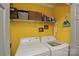 Bright laundry room with white appliances, storage shelves, and yellow walls at 4810 Shea Ct, Monroe, NC 28110