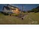 A twilight view of a lush backyard with a vegetable garden and a patio seating area at 528 Rock Skip Way, Fort Mill, SC 29708
